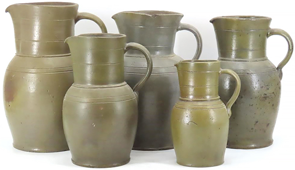 One feature of the 19th-century stoneware pitchers from the pottery of J. M. Hickerson of Strasburg, Virginia, is their tall, collar-like necks. This assembled group of five graduated Hickerson-attributed pitchers ranges in capacity from a half-gallon to two gallons; the tallest stands 14½