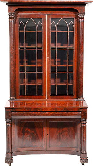 Gothic Revival carved mahogany bureau bookcase, circa 1830, attributed to Meads and Alvord, New York, the back inscribed “B Bourne Glen Cove,” with a stepped cornice, arched frieze, columnar supports flanking glazed doors, a foldout writing surface, a frieze drawer, incurvate paneled doors with flanking columnar supports, carved feet, and casters, 93¼