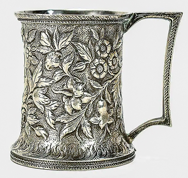 The mark on this silver mug by S. Kirk & Son dates it to 1869-90. The slightly waisted form features a squared handle and dense allover floral repoussé design. Standing 3½