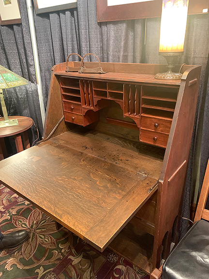 JMW Gallery, Cambridge, Massachusetts, offered this Stickley Brothers drop-front desk with strap copper hardware for $1995. Besides the cubbyholes, it has four drawers inside and two small drawers and one large drawer in the base. On top are copper Roycroft bookends for $495 and a Handel floral reverse-painted lamp for $895.