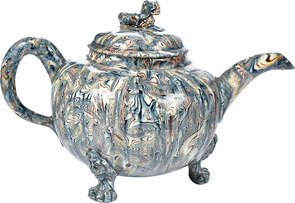 This shimmering lidded Staffordshire agateware teapot would attract attention on any tea table. Lions are everywhere—from the finial to the feet to the terminals on the feet. The 5¼