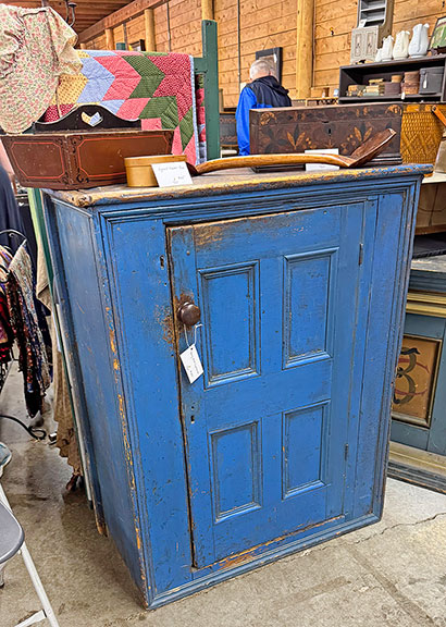 The early blue cupboard from Dean Witham of Red Clover Antiques, Westford, Vermont, who shared a booth with Cooper O’Connell, was $745. The signed Shaker box on it was $195; the knife box in original paint, $150; the marquetry document box, $450. We missed the price of the double-sided scoop.