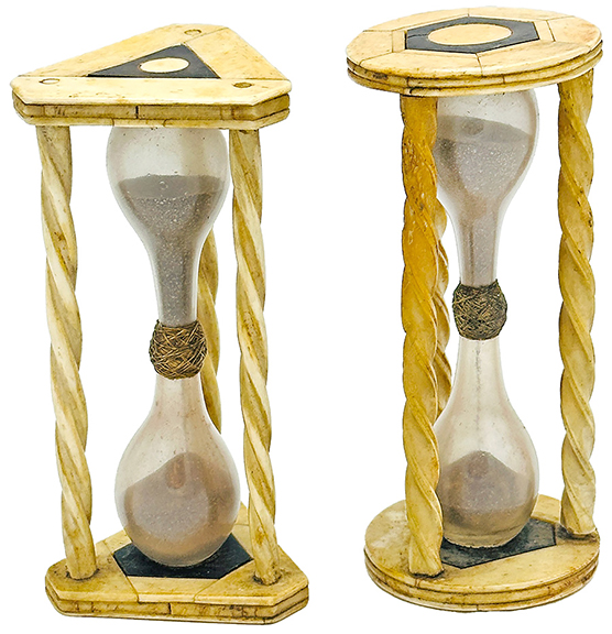 Two 19th-century sand timers with spiral-carved columns of inlaid bone and twine-wrapped glass bulbs, one with triangular feet and the other with circular feet, sold for $1216 (est. $300/500). Both stand 4¾