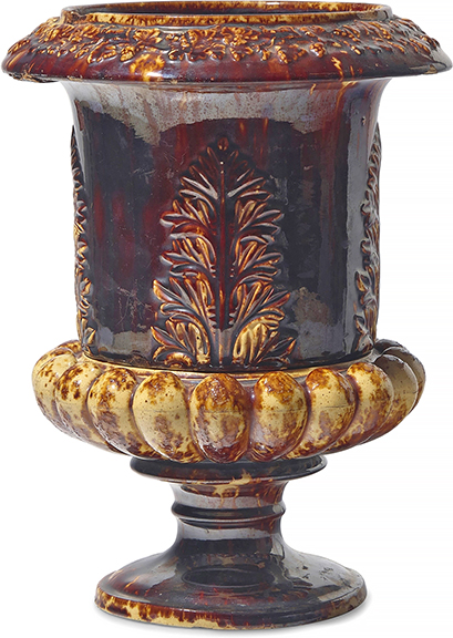 This rare Rockingham-glazed earthenware two-piece flower pot/urn, United States Pottery Co. (1852-58), Bennington, Vermont, 1849-58, the upper section with a hole for drainage, the lower section with a basin for water, 13¼