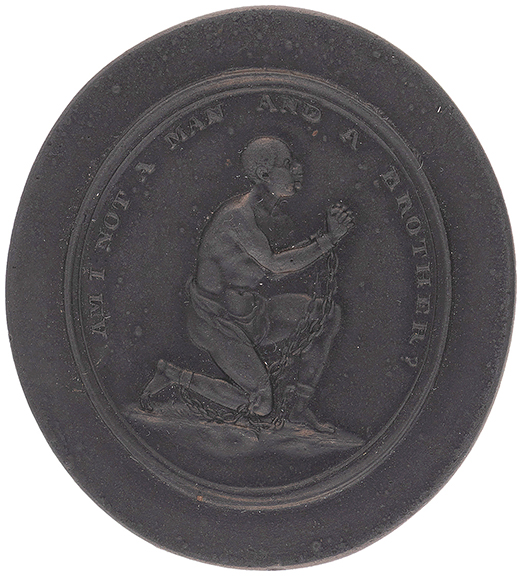 This late 18th-/early 19th-century Wedgwood black basalt oval medallion was designed by Josiah Wedgwood and others for the Society for the Abolition of the Slave Trade in 1787. Marked “Wedgwood,” it depicts an enslaved man pleading for humanity. Text above him reads “Am I Not A Man And A Brother?” Measuring 1½