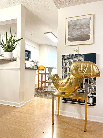 Looking toward the kitchen is a gilt ride-on playground toucan, bought from Sheelin Wilson, who has a gilding studio in New York City. On the wall is a painting on a photograph by Philadelphia artists Natasha Hulme, a painter, and Michael Penn, a photographer. The subject is the Pearl Paint store, a fixture for decades on Canal Street, New York City. In the kitchen is an aluminum and stainless steel table from a store in Georgia.