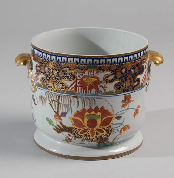 This circa 1805 ironstone ice bucket was one of seven lots of similarly decorated tableware made by the Turner family of potters in England. Decorated in a brightly colored Imari-inspired water lily and willow pattern, the cylindrical body measures 6¾