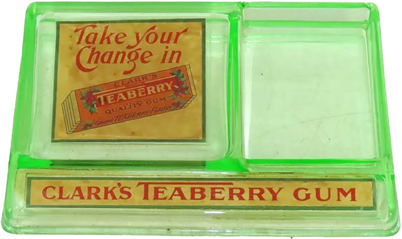 The countertop Clark’s Teaberry Gum display/sales stimulator is made of green uranium glass. The customer is enticed to “Take your Change in Clark’s Teaberry Quality Gum.” There is a space for sticks or packs of gum to be displayed. The 6