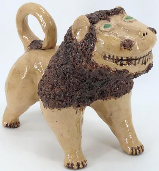 This unmarked glazed lion figure is in the style of the iconic Solomon Bell example pictured on the cover of The Pottery of the Shenandoah Valley Region by H. E. Comstock (1994), published by the Museum of Early Southern Decorative Arts. The smiling lion, with incised facial features, a dark coleslaw mane, copper-glazed eyes, and a curved tail, 10