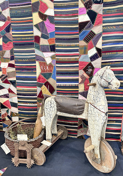 Crazy quilt, $650; painted basket, $345; carved wood doll with stuffed fabric arms (partially visible), $850; small tramp art frame with hearts at the corners, $175; wooden horse with leather seat/saddle, 31