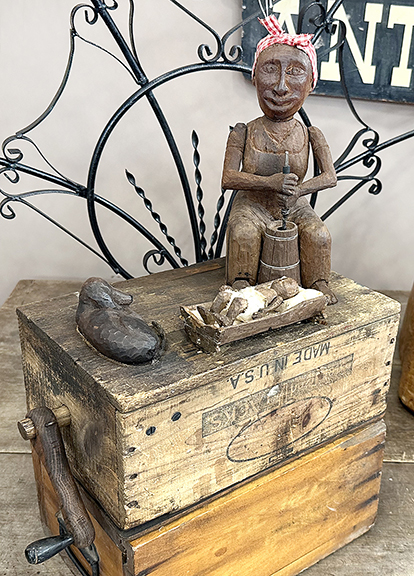 Mammy automaton made of carved wood, $795 from Karen Jack. When the device is cranked, the woman moves the handle of the butter churn and taps her foot to rock the cradle, while the dog wags its tail. “Lyle Shelton” is written on the back of the crate. The mammy stands 10