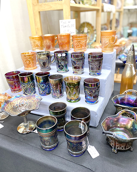 Karen Stoiber of Menomonee Falls, Wisconsin, and Mary Lou Haas of Hartland, Wisconsin, linger over a display of carnival glass at the space of Joe Baran from Arlington Heights, Illinois. The mugs and tumblers were tagged $10 each. 