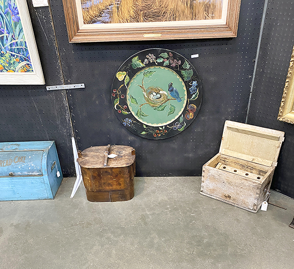 Ron Christman Antiques and Art, Wales, Wisconsin, had a packed space including, at floor level from left, a $125 blue-painted bread box, a wooden pantry box with a top handle for $155, and a $125 white box-shaped butter churn. Above is a round wooden hand-painted plaque decorated with a bluebird and nest for $165. Not seen is a $475 pair of circa 1840s twin wooden beds, each converted for use with a modern mattress and box spring. 