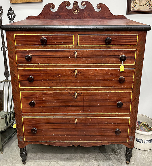Greg K. Kramer & Co., Robesonia, Pennsylvania, featured this 1851 two-color-ground painted and decorated Soap Hollow chest of drawers for $12,500. The top crest features six stylized floral or pinwheel motifs.